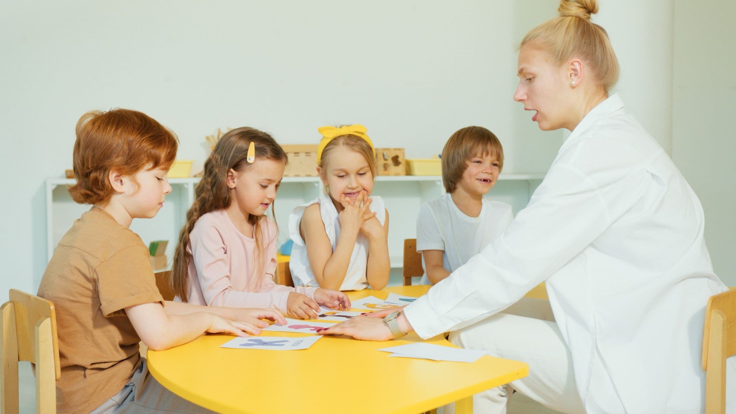 A teacher with young children at a classroom table